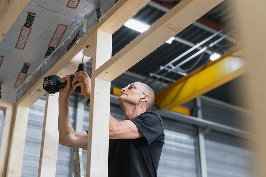 Productiemedewerker assembleert houten frame van modulaire unit met PIR-isolatieplaten zichtbaar in het plafond