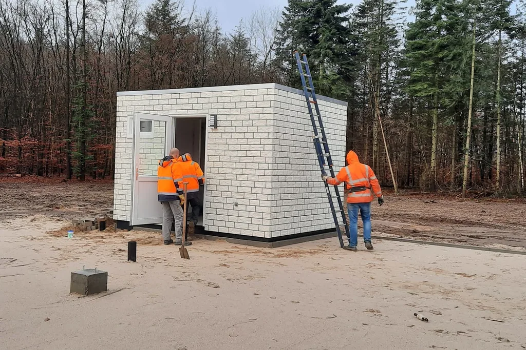 Bouwteam plaatst modulaire unit op een afgelegen bouwlocatie in het bos met behulp van een vrachtwagen